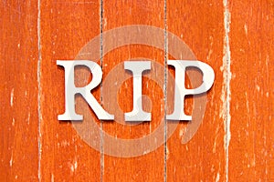 Alphabet in word RIP abbreviation of rest in peace on old red color wood plate background