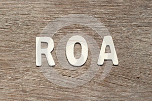 Alphabet in word ROA Abbbreviation of Return on assets on wood background