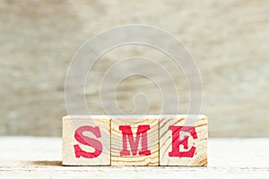 Alphabet in word SME abbreviation of Small and medium sized enterprises on wood background