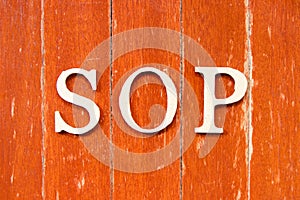 Alphabet in word SOP Abbreviation Standard Operating Procedure on old red color wood plate background