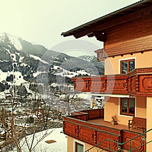 Alpin house with wooden balcony in winter mountain village, Alps