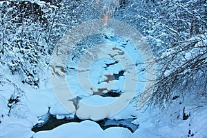 Alpine brook nature richly in snow and nearly frozen