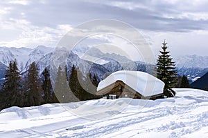 Alpine chalet sunk in deep snow in winter with thick snow on roof in the Swiss Alps