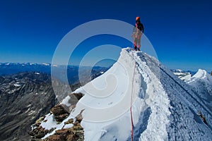 Alpine climber, alpinist on a sharp knife edge of snow mountain in the Alps