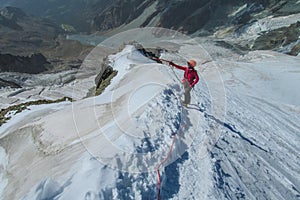 Alpine climber, alpinist on a sharp knife edge of snow mountain in the Alps