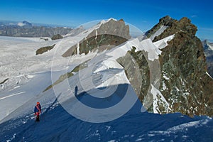 Alpine climber on rock and snow mountain ridge