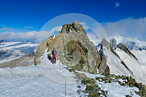 Alpine climber on rock and snow mountain ridge