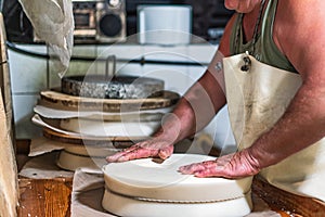 An alpine dairyman during the creation of the typical local Bergamasque northern Italian cheese wheel