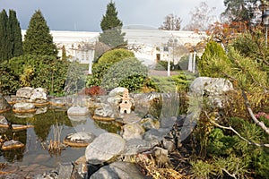 Alpine hill in the park with evergreen plants and a pond