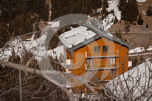 Alpine house or hotel in the valley of Meribel in france on late winter or early spring. Low amount of snow on the house and