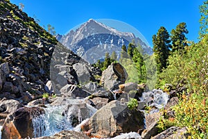 Alpine landscape with a cascade of water on a mountain stream