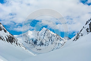 Alpine landscape with peaks covered by snow and clouds