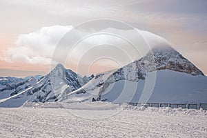 Alpine landscape with peaks covered by snow and clouds, beautiful colors at the top of a glacier.