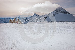 Alpine landscape with peaks covered by snow and clouds, beautiful colors at the top of a glacier.