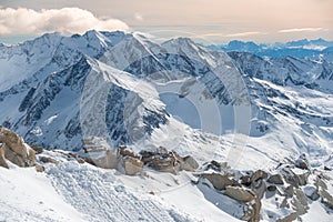 Alpine landscape with peaks covered by snow and clouds, beautiful colors at the top of a glacier