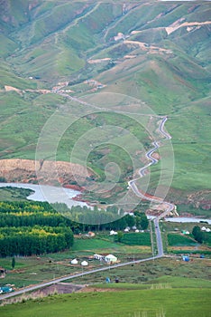 Alpine meadow with winding road in mountain ranges in the morning