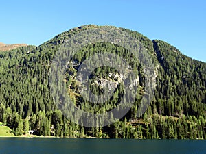 Alpine mountain Seehorn (2238 m) covered with evergreen forest above the tourist and sports mountain lake Davos