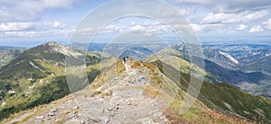 Alpine panorama with mountain ranges and hiker going through them on a sunny day, Slovakia, Europe