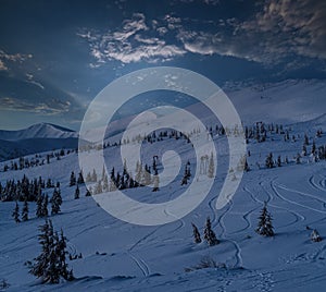 Alpine resort ski lift with seats going over the pre sunrise night mountain skiing freeride slopes and fir tree groves. Svydovets