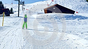 Alpine skier boy go up holding t-bar ski lift on sunny day