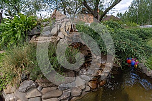 Alpine slide with stones, various ornamental plants and a waterfall