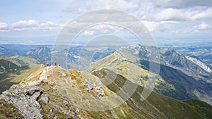 Alpine vista with mountain ranges and hiker going through them on a sunny day, Slovakia, Europe