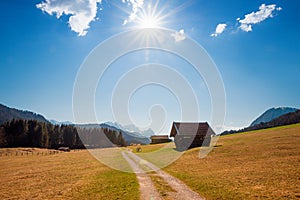 Alpine walkway near Gerold, autumnal landscape with huts and bright sun, blue sky with clouds upper bavaria