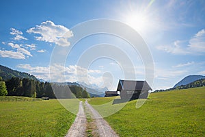 Alpine walkway near Gerold, spring landscape with huts and bright sun, blue sky with clouds