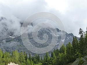 Alpine walley with coniferous forest and rocky hill with thunder cloud in the background, Bavarian Alps mountains mountain weather