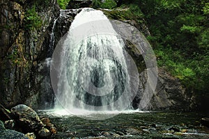 Alpine waterfall Korbu in Altai in a rocky gorge in summer