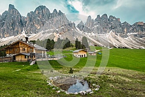 Alpine wooden chalets on the green fields, Dolomites, Italy