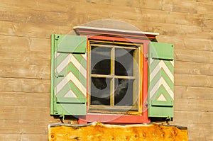 Alpine wooden house facade with orange window