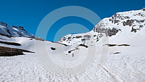 Alpinist hiking ski touring on snowy slope towards the mountain summit. Concept of conquering adversities and reaching the goal.