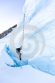 Alpinist mountaineer climb ladder over ice crevasse