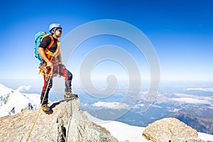 Alpinist mountaineer standing rock cliff mountain summit