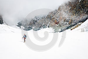 Alpinist moutaineer standing glacier looking rock cliffs