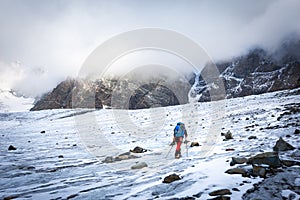 Alpinist moutaineer walking glacier towards rock cliffs