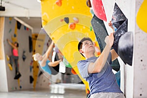 Alpinist practicing indoor rock-climbing on artificial boulder without safety belts