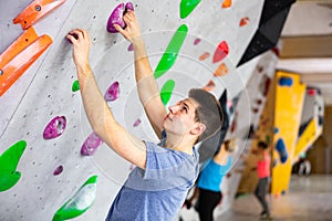 Alpinist practicing indoor rock-climbing on artificial boulder without safety belts photo