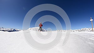 Alpinist ski touring on the ridge with expansive snowcapped mountain view in a bright sunny day.