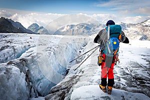 Alpinist standing glacier above crevasse mountains ridge view