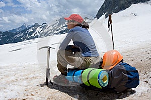 Alpinist woman sitting on her backpack photo