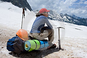 Alpinist woman sitting on her backpack photo
