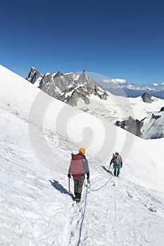 Alpinists with rope and climbing tools on Col du Midi in front of Grandes Jorasses, Mont Blanc massif in the French Alps, Chamonix