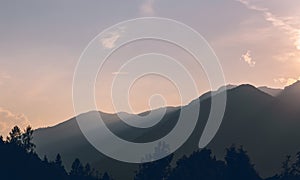 Alps mountain silhouette with trees and sunset sky. Austria landscape