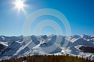 Alps mountains with snow in winter, sun and blue sky