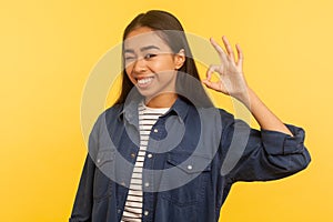 Alright, I agree! Portrait of cheerful smiling girl in denim shirt showing ok hand gesture, approval cool symbol