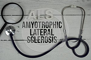 ALS Amyotrophic Lateral Sclerosis text with Stethoscope on wooden background