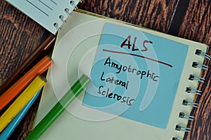 ALS - Amyotrophic Lateral Sclerosis write on sticky notes isolated on Wooden Table