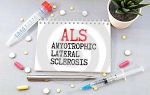 ALS Amyotrophic Lateral Sclerosis written in notebook on white table photo